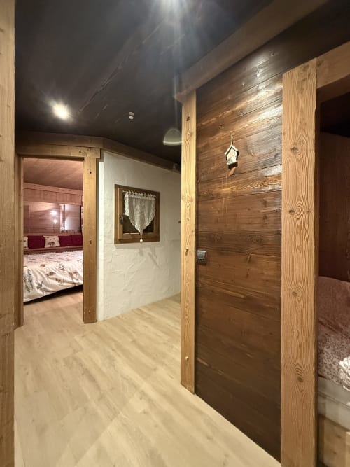 Couloir de l'appartement La Plagne Ski Confort avec poutres apparentes, revêtement clair et accès à la chambre avec vue sur les montagnes