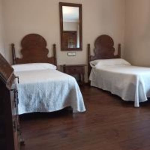 Habitación doble con dos camas individuales en Pension Castio de Santillana del Mar, España, con muebles de madera y decoración blanca