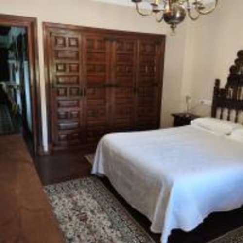 Habitación doble espaciosa en Pension Castio, Santillana del Mar, con cama blanca, armario de madera y vistas a la montaña