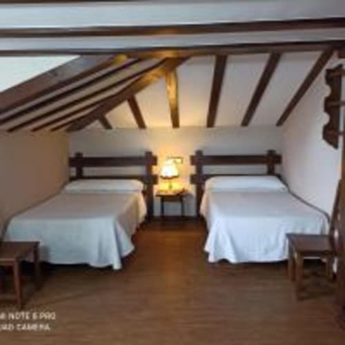 Habitación doble con vigas de madera en Pensión Castio, Santillana del Mar, con dos camas y vistas a la montaña
