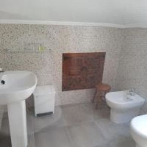 Cuarto de baño de Pensión Castio en Santillana del Mar con inodoro, bidé, lavamanos y paredes alicatadas