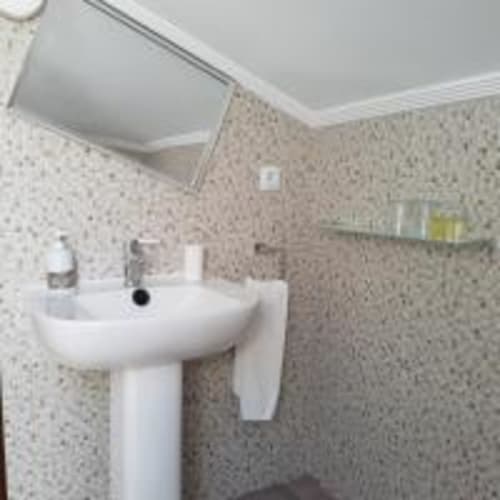 Baño moderno con lavabo pedestal blanco y paredes con azulejos texturizados beige en Pension Castio, Santillana del Mar