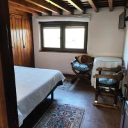 Acogedor dormitorio doble en Pensión Castio, Santillana del Mar, con muebles de madera, cama, escritorio, ventanas y vistas a las montañas