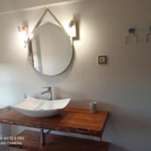 Lavamanos moderno del hotel Pension Castio con espejo ovalado y lavabo blanco en Santillana del Mar