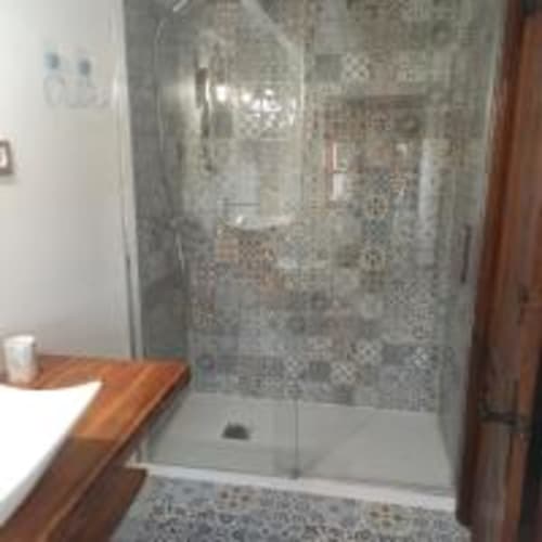 Moderna cabina de ducha con paredes de azulejos grises y base blanca en habitación del hotel Pensión Castio, Santillana del Mar
