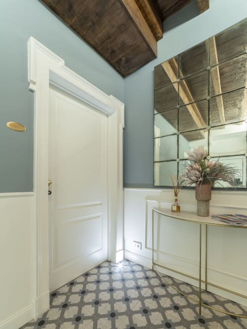 Ingresso moderno presso YOUnique Boutique Rooms Milano con porta bianca, pavimento in piastrelle decorate e specchio in stile industriale