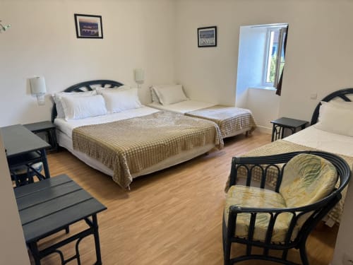Spacieuse chambre quadruple à l'Hôtel Du Rocher au Caylar avec lits multiples, parquet et vue sur la ville