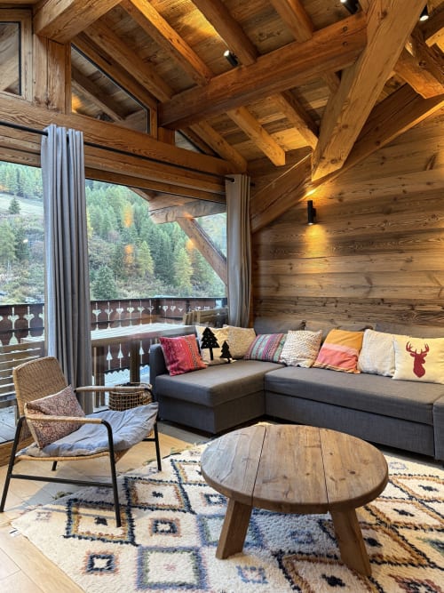 Séjour cozy à l'alpage dans l'appartement de ski La Plagne : poutres en bois, canapé gris, vue montagne et cheminée