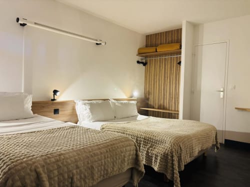 Chambre d'hôtel moderne à l'Hôtel Du Rocher au Caylar avec deux lits, bureau et vue sur la ville