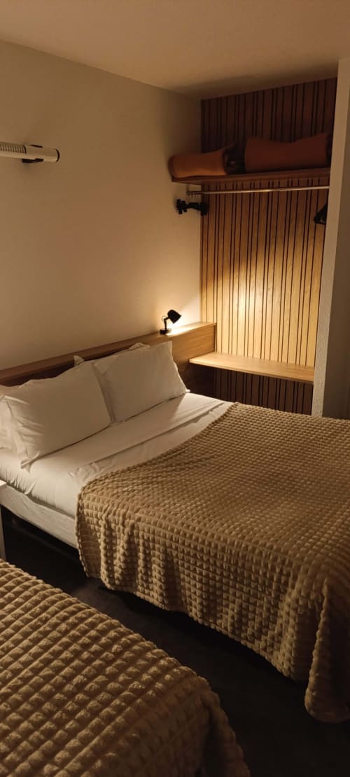 Chambre triple confortable à l'Hôtel Du Rocher au Caylar avec literie blanche, éclairage chaleureux et espace bureau intégré