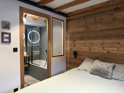 Chambre moderne avec mur en bois et salle de bain attenante dans un appartement de ski à La Plagne
