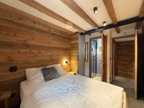 Chambre chaleureuse à La Plagne Ski Confort avec poutres en bois, lit queen-size, salle de bain privée et accès à vue montagne.