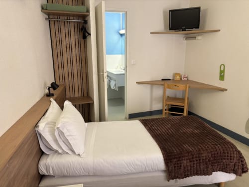 Confort Twin room at Hôtel Du Rocher in Le Caylar with bed, TV, work desk, and bathroom view