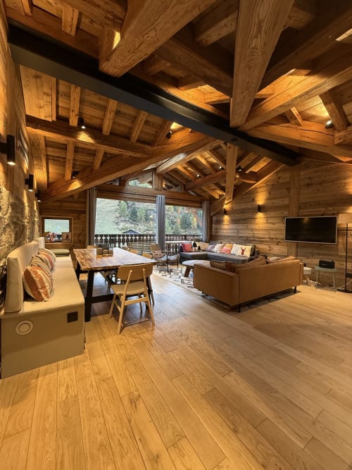 Intérieur de chalet en bois luxueux à La Plagne avec poutres apparentes, vue montagne, salle à manger et équipements modernes