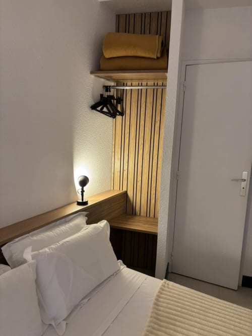 Chambre confortable à l'Hôtel Du Rocher avec literie blanche, bureau en bois, applique murale et radiateur vertical à Le Caylar