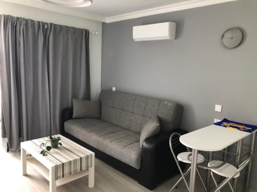 Moderna sala de estar en Apartamentos Aloe con sofá gris, mesa de café blanca y zona de comedor en Playa del Inglés