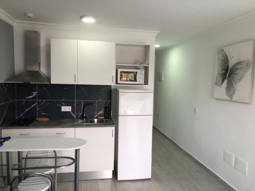 Cocina moderna en la Suite Aloe de Apartamentos Aloe, Playa del Inglés con muebles blancos, backsplash de mármol negro y