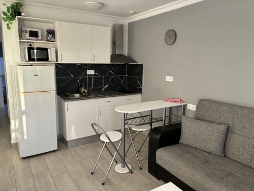 Moderna cocina con backsplash de mármol negro, gabinetes blancos, mesa de comedor y sofá gris en apartamento Suite ALOE, Playa