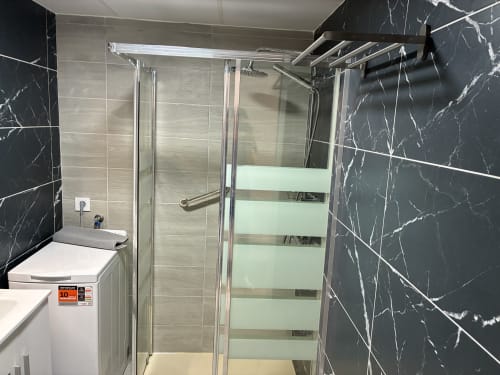 Moderna cabina de ducha con puertas de cristal y paredes revestidas en mármol en el baño de la Suite Aloe Lovers, Playa del Inglés