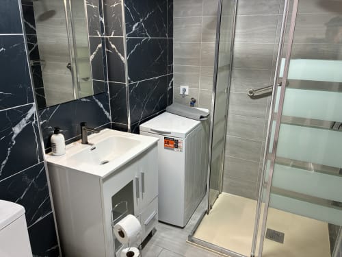 Baño moderno en la Suite Aloe Lovers de Apartamentos Aloe, Playa del Inglés, con azulejos de mármol negro y lavabo blanco.