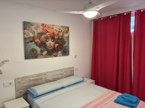 Dormitorio de la Suite Lovers ALOE en Apartamentos Aloe, Playa del Inglés con cama, obras de arte floral y cortinas rojas