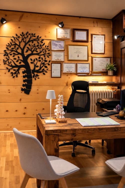Ufficio moderno dell'Hotel Moderno Restaurant a Serina con scrivania in legno, arte murale con albero e certificati incorniciati