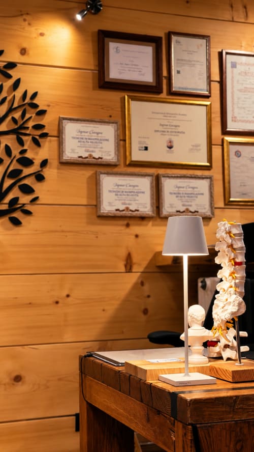 Ufficio ristorante Hotel Moderno con certificati incorniciati su parete in legno, lampada da scrivania e oggetti decorativi a Serina, Italia