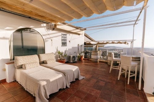 Soleada terraza en la azotea del La Vista Medina Studio Deluxe en Medina Sidonia con tumbonas, zona de comedor y vistas a la ciudad