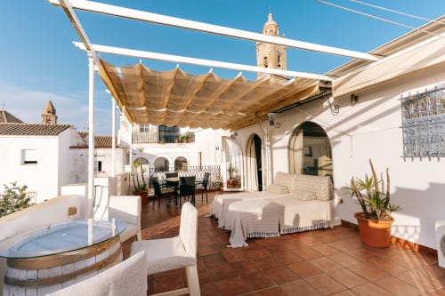 Terraza soleada de La Vista Medina Studio Deluxe con toldo retráctil, asientos, bañera de hidromasaje y vistas a la iglesia de Medina Sidonia
