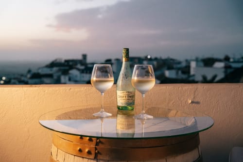 Botellas y copas de vino Coft Twist en terraza con vistas a Medina Sidonia al atardecer