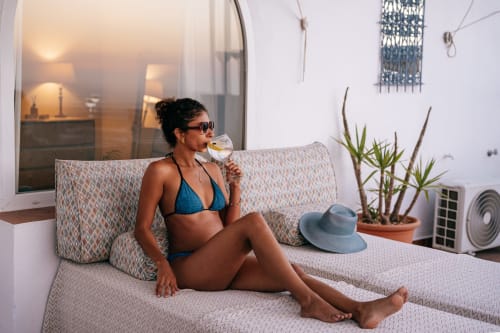 Mujer disfrutando vino en el balcón de La Vista Medina Studio Deluxe con vistas a la ciudad y plantas en macetas