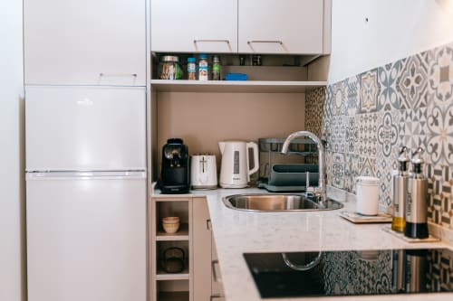 Pequeña cocina moderna en estudio La Vista Medina Stays con electrodomésticos blancos, salpicadero con patrón y fregadero de acero inoxidable