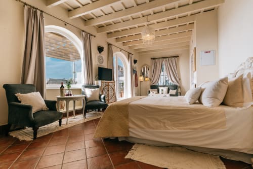 Estudio de lujo en Medina Sidonia con ventanas arqueadas, techo de vigas, cama king, sillón verde y terraza