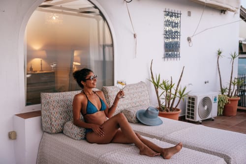 Mujer disfrutando de vino en la terraza de La Vista Medina Studios en Medina Sidonia, España, con vistas a la ciudad y suculentas.