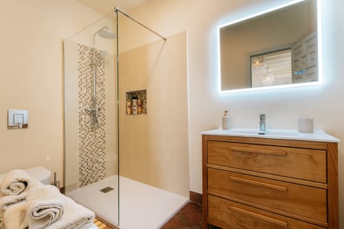 Baño moderno en La Vista Medina Studio Deluxe con ducha de cristal, tocador de madera y espejo iluminado