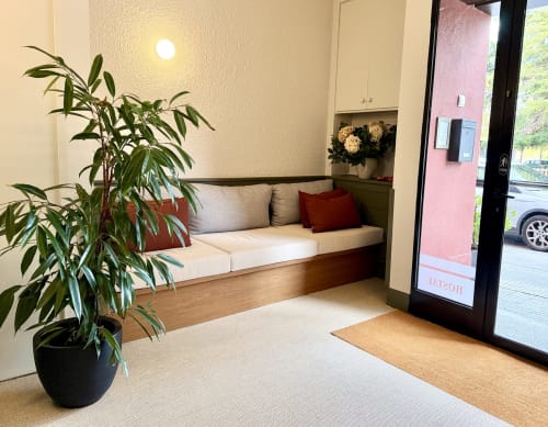 Acogedor área de recepción en el Hostal Estació de Puigcerdà con banco empotrado, planta en maceta y puerta de cristal