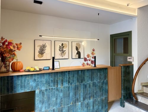 Recepción del Hostal Estació en Puigcerdà con azulejos color teal, flores de otoño y arte botánico en la pared