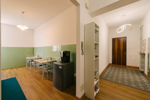 Moderna zona living a Verona con pareti verdi e bianche, tavolo da pranzo, elettrodomestici e pavimento in legno