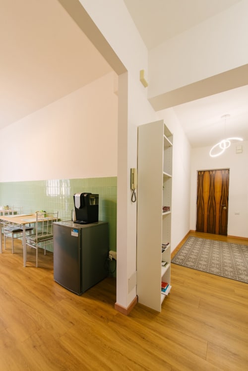 Cucina moderna con frigorifero nero, piastrelle verdi, pavimenti in legno e scaffali aperti