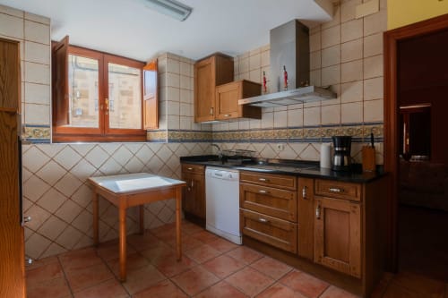 Spacious kitchen in La Viña 1 apartment at Casas Rurales with wooden cabinets, dishwasher, and dining table