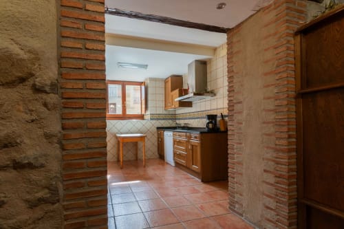Kitchen area in La Viña 1 apartment at Casas Rurales La Viña with wooden cabinetry, terracotta tiles, and brick archways