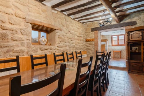 Rustic stone dining room with wooden beams and table at Casas Rurales La Viña in Cuzcurrita de Río Tirón