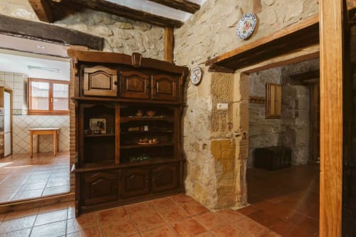 Rustic stone apartment interior at Casas Rurales La Viña with wooden beams, dark wooden furniture, terracotta floors, and