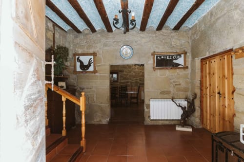 Rustic stone interior at Casas Rurales La Viña with exposed beams, terracotta floors, wooden doors, and traditional Spanish
