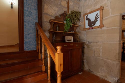 Wooden staircase with rustic furnishings and shelving in Casas Rurales La Viña apartment entryway, Cuzcurrita de Río Tirón.
