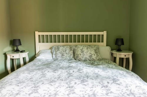 Bedroom with cream headboard, green walls, floral bedding, and matching nightstands at Casas Rurales La Viña