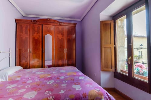Purple bedroom with wooden wardrobe and pink floral bedding at Casas Rurales La Viña, Cuzcurrita de Río Tirón