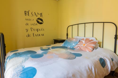 Cozy bedroom at Casas Rurales La Viña with yellow walls, metal bed frame, colorful bedding, and Spanish wall text in