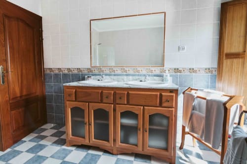 Spacious bathroom at La Viña apartment with wooden vanity, dual sinks, large mirror, and checkered tile flooring.
