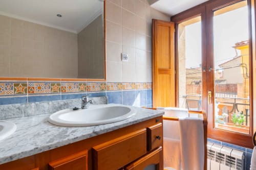 Bright bathroom at Casas Rurales La Viña with marble countertop, round sink, wooden vanity, and balcony views in Cuzcurrita